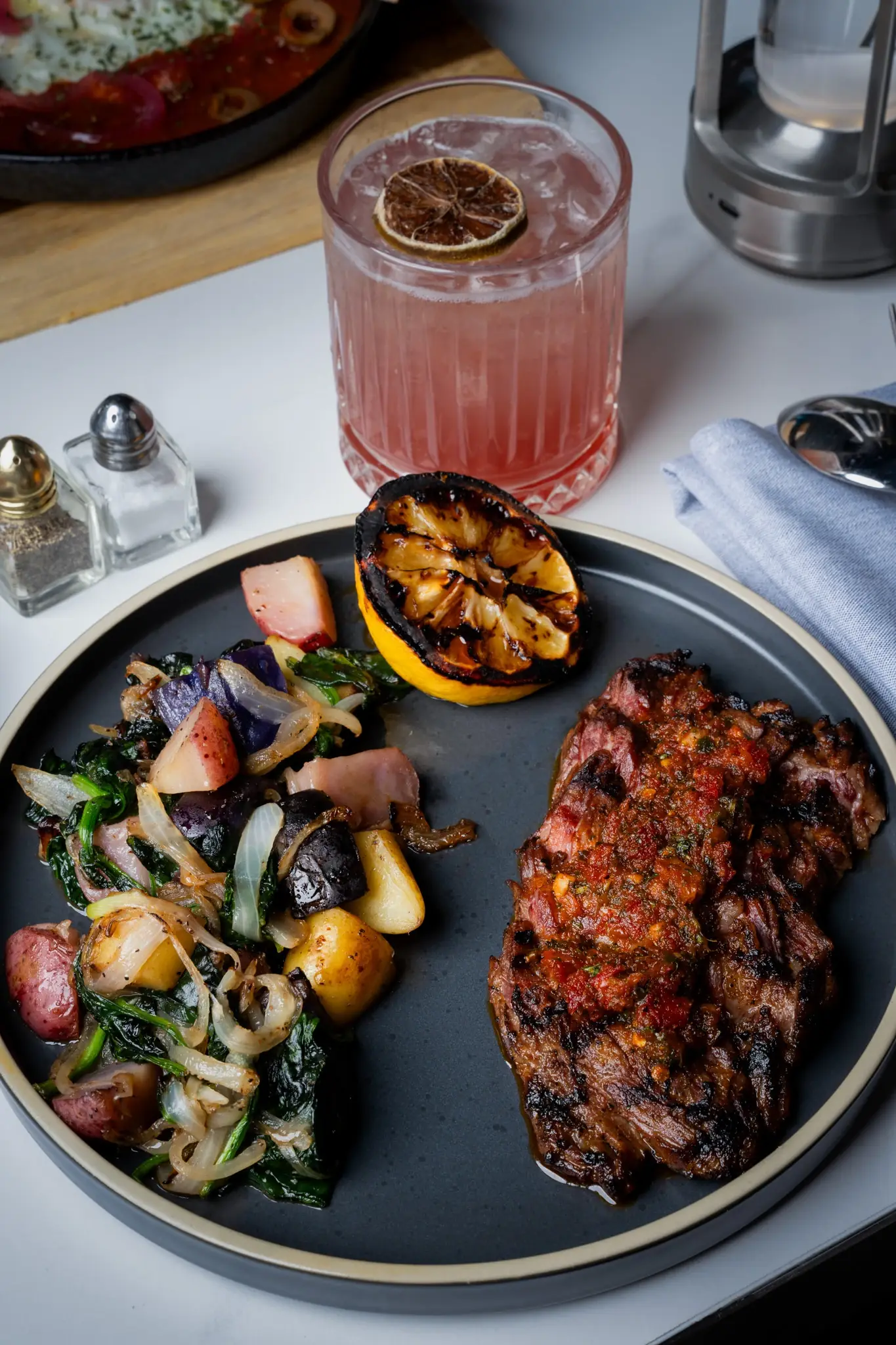 Grilled steak with potatoes and a cocktail on a marble table at Siena, Alpharetta