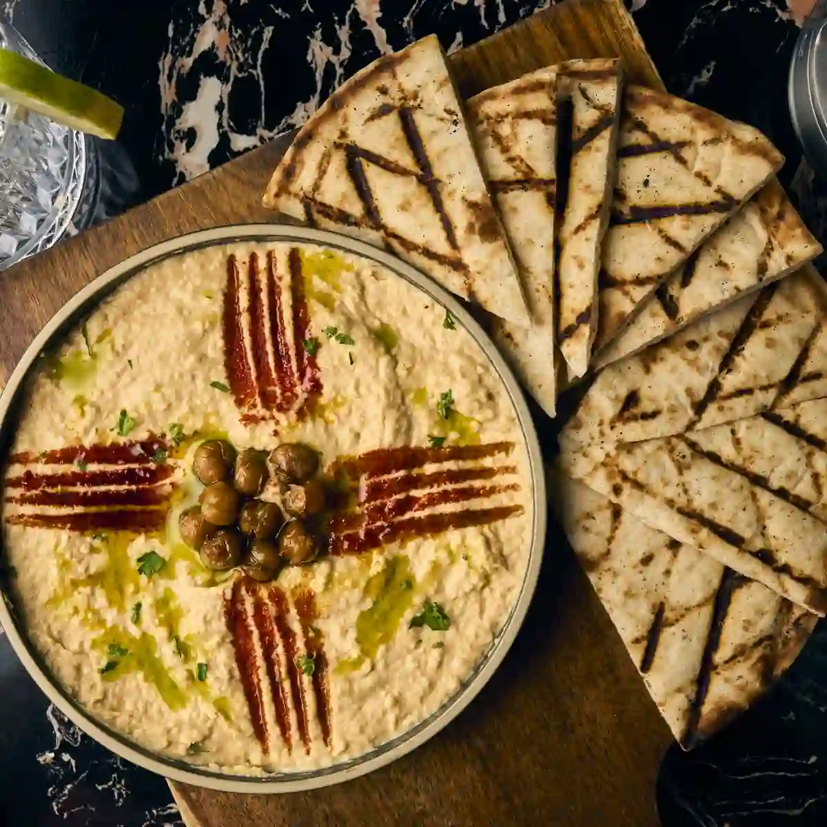 Hummus with olive oil and grilled pita on a board, a happy hour plate in Alpharetta